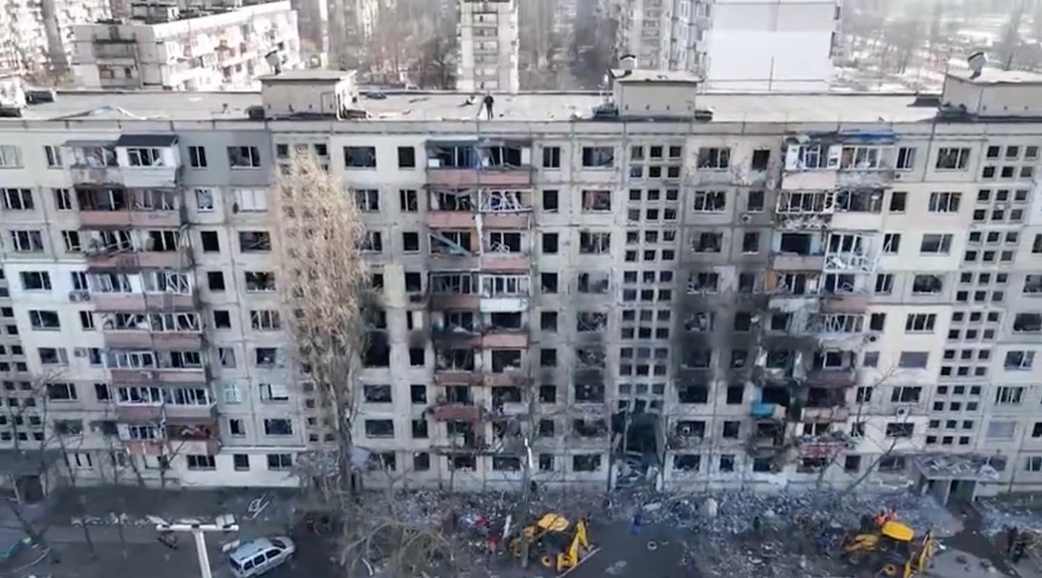 Drone footage of a shelled Kyiv apartment block with blown-out windows and rubble.