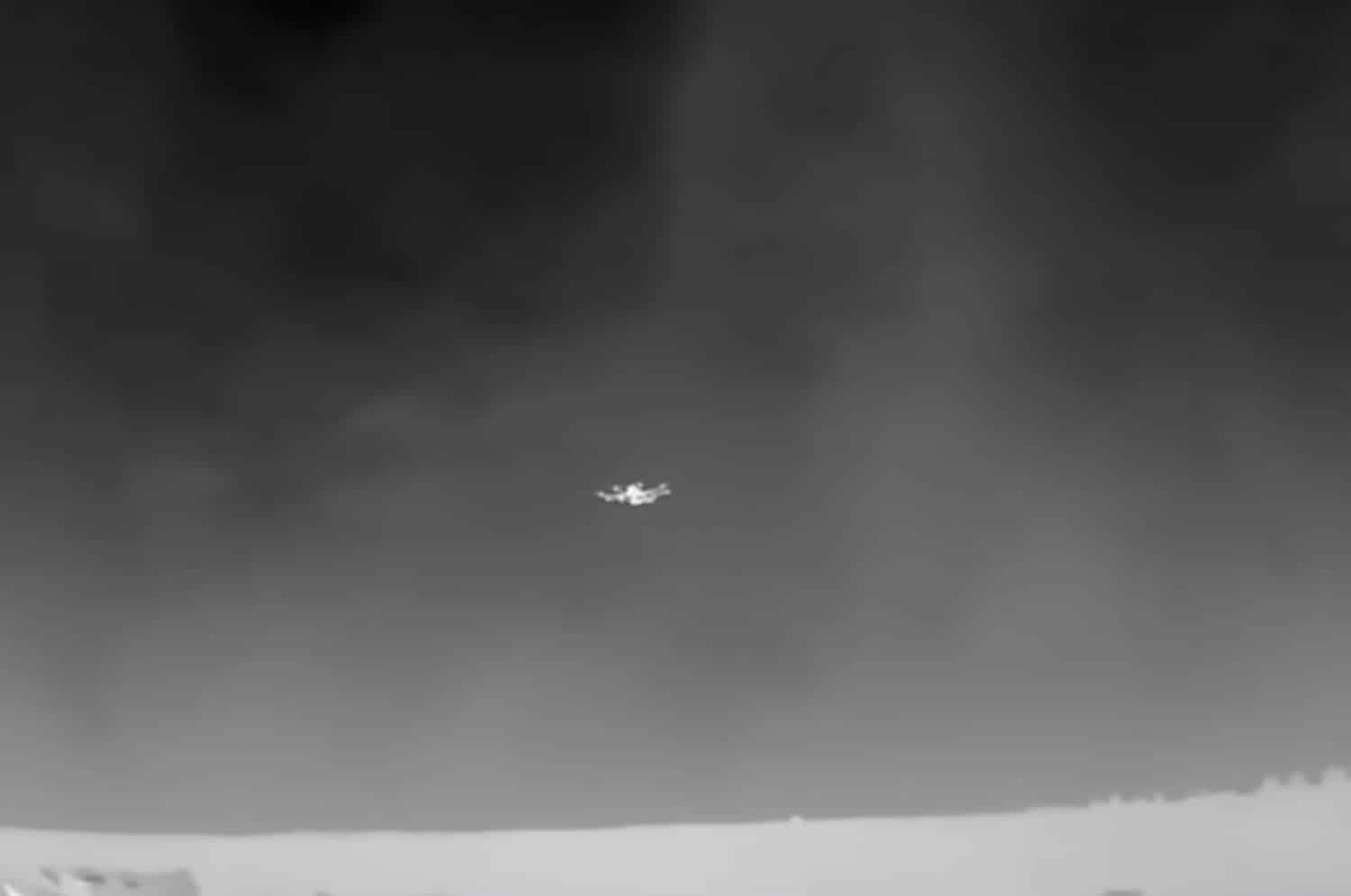 Thermal frame of a small quadcopter hovering against a dark night sky.