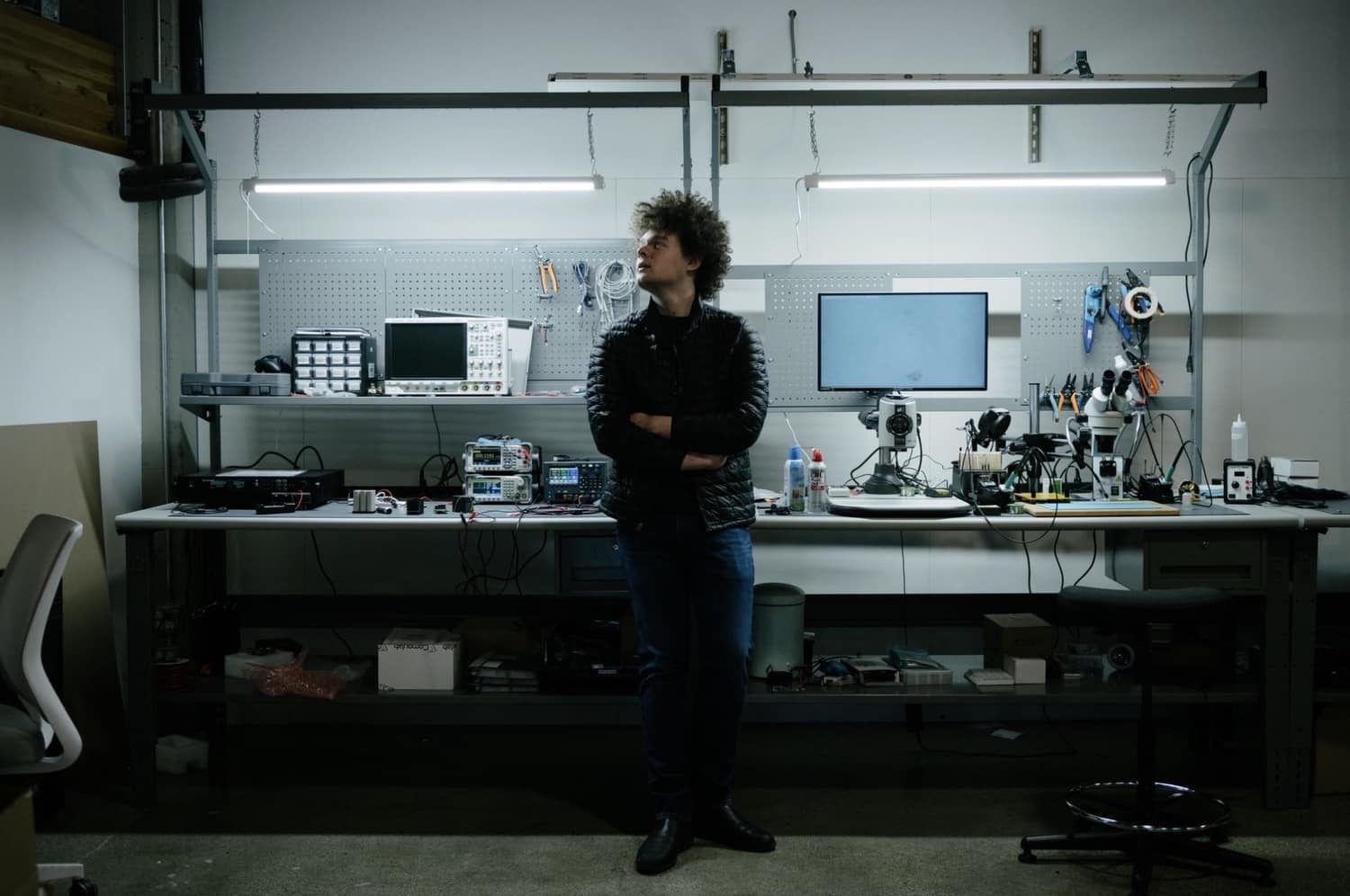 Engineer standing in a drone electronics workshop lined with benches and test gear.