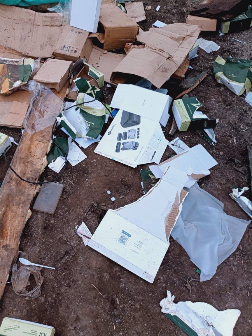 Empty DJI Mavic 3 Combo boxes piled in rubble beside a damaged military truck.