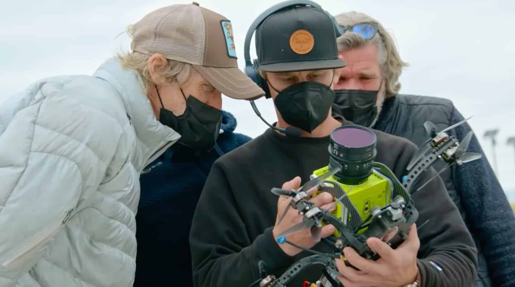Crew members inspect a cinelifter FPV drone carrying a cinema camera on set.