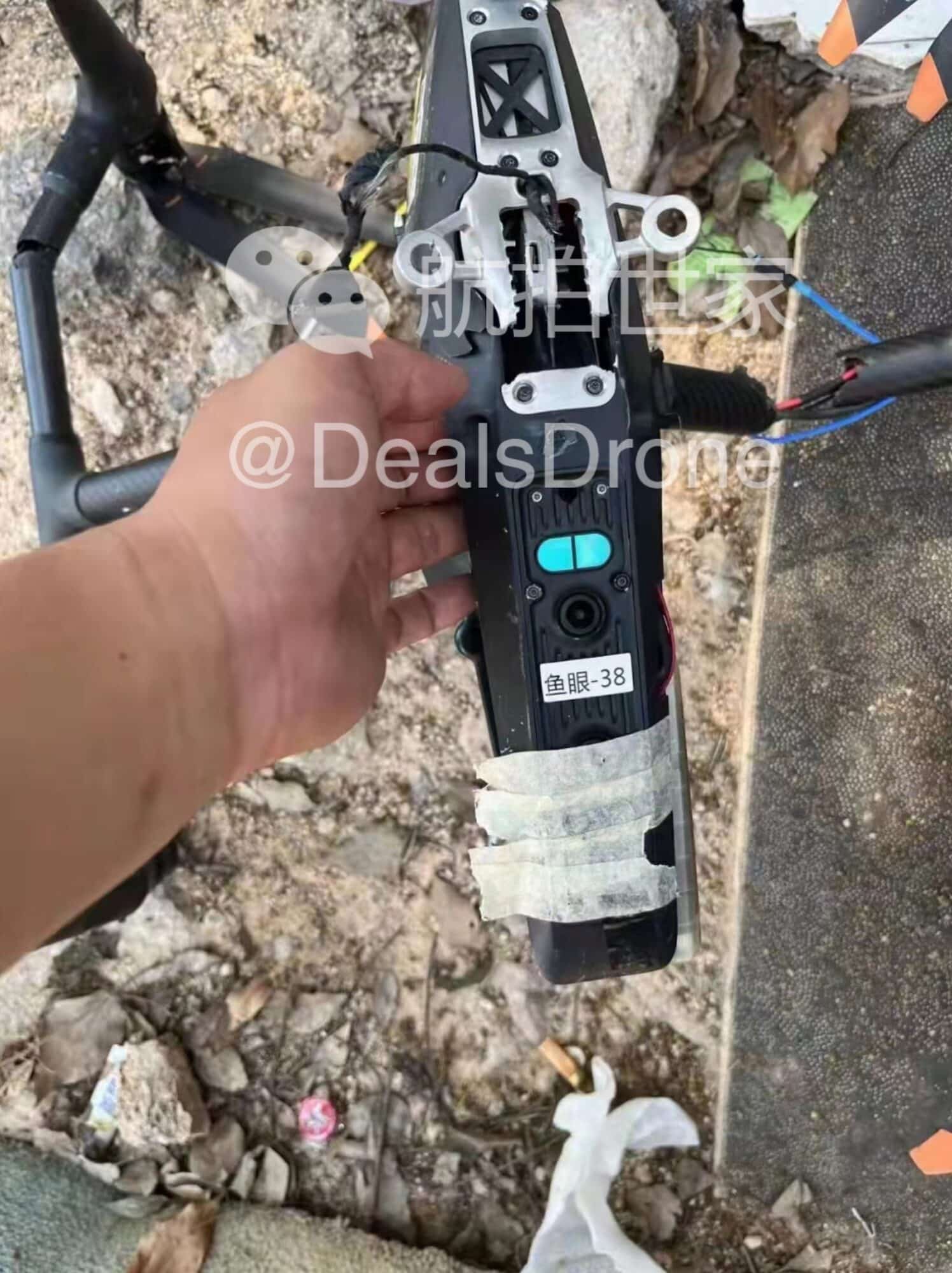 Hand holding a taped, broken arm from the crashed Inspire 3 prototype.