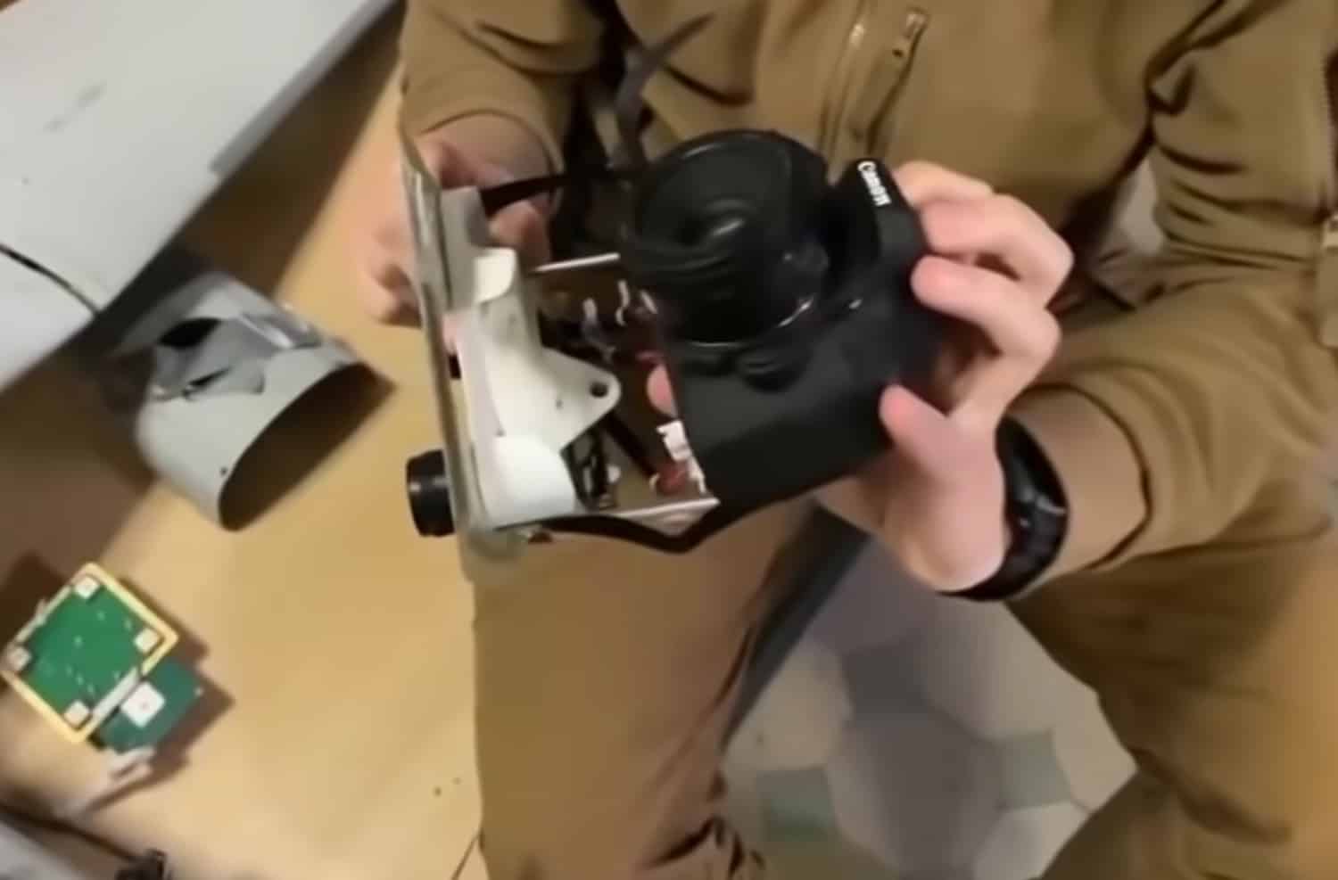 A soldier lifts out the camera mount assembly with the Canon body still attached.