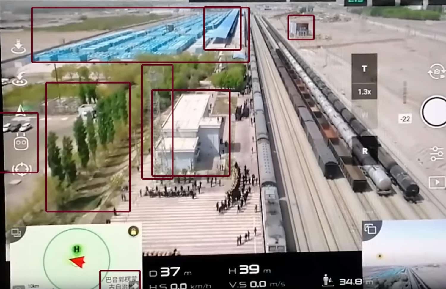 Drone video frame with landmarks marked: a cell tower, blue buildings, a car park and train tracks.