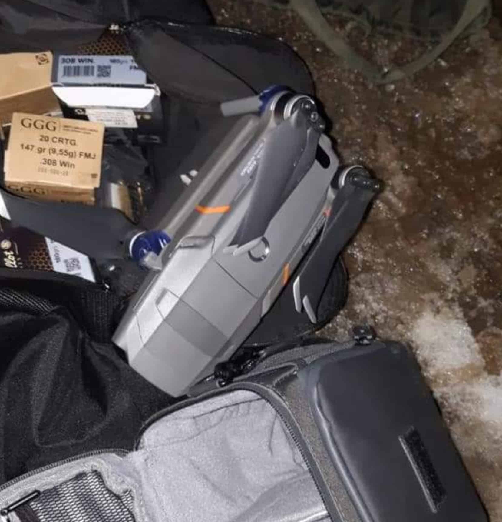 Seized DJI Mavic 2 Enterprise and backpacks laid out beside ammunition boxes.