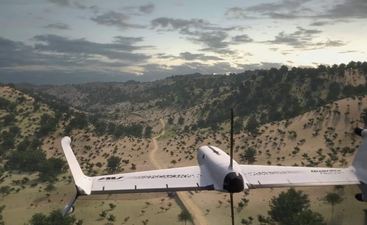 Quantix Recon drone in horizontal flight over scrubby hills and a dirt road.