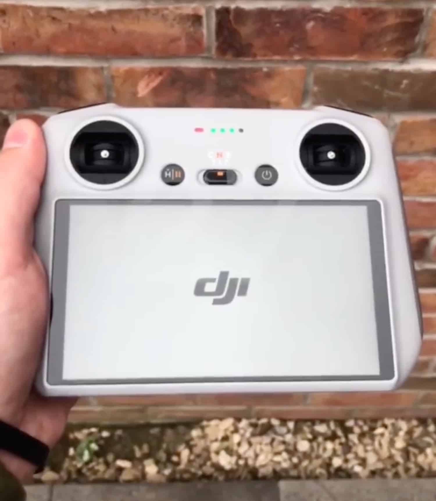 Hand holding the DJI RC as its screen shows the startup logo.