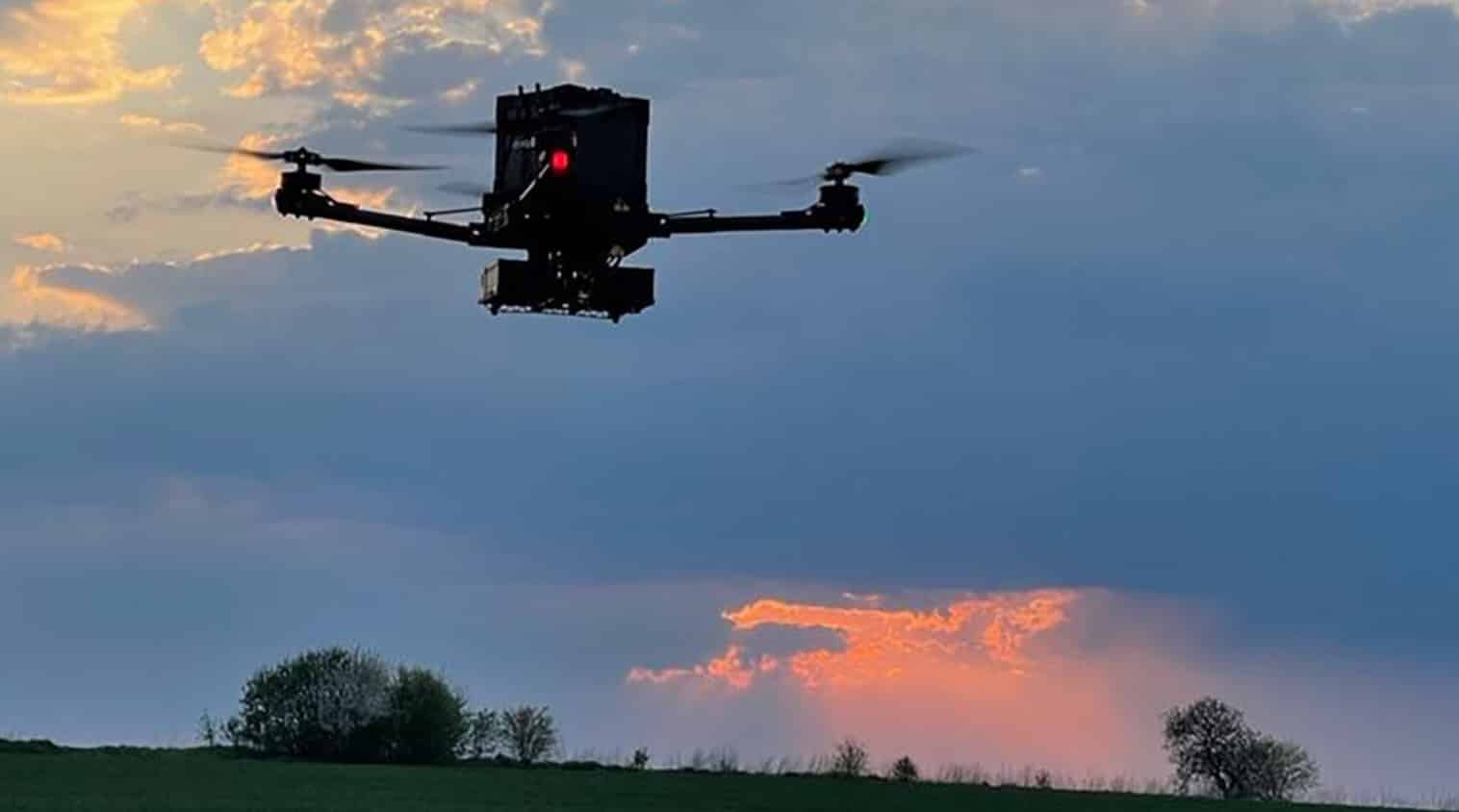 Draganfly medical response quadcopter hovering above a field at sunset.