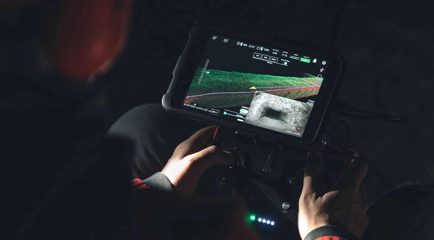 Operator holding a tablet displaying a green live LiDAR scan of a tunnel.