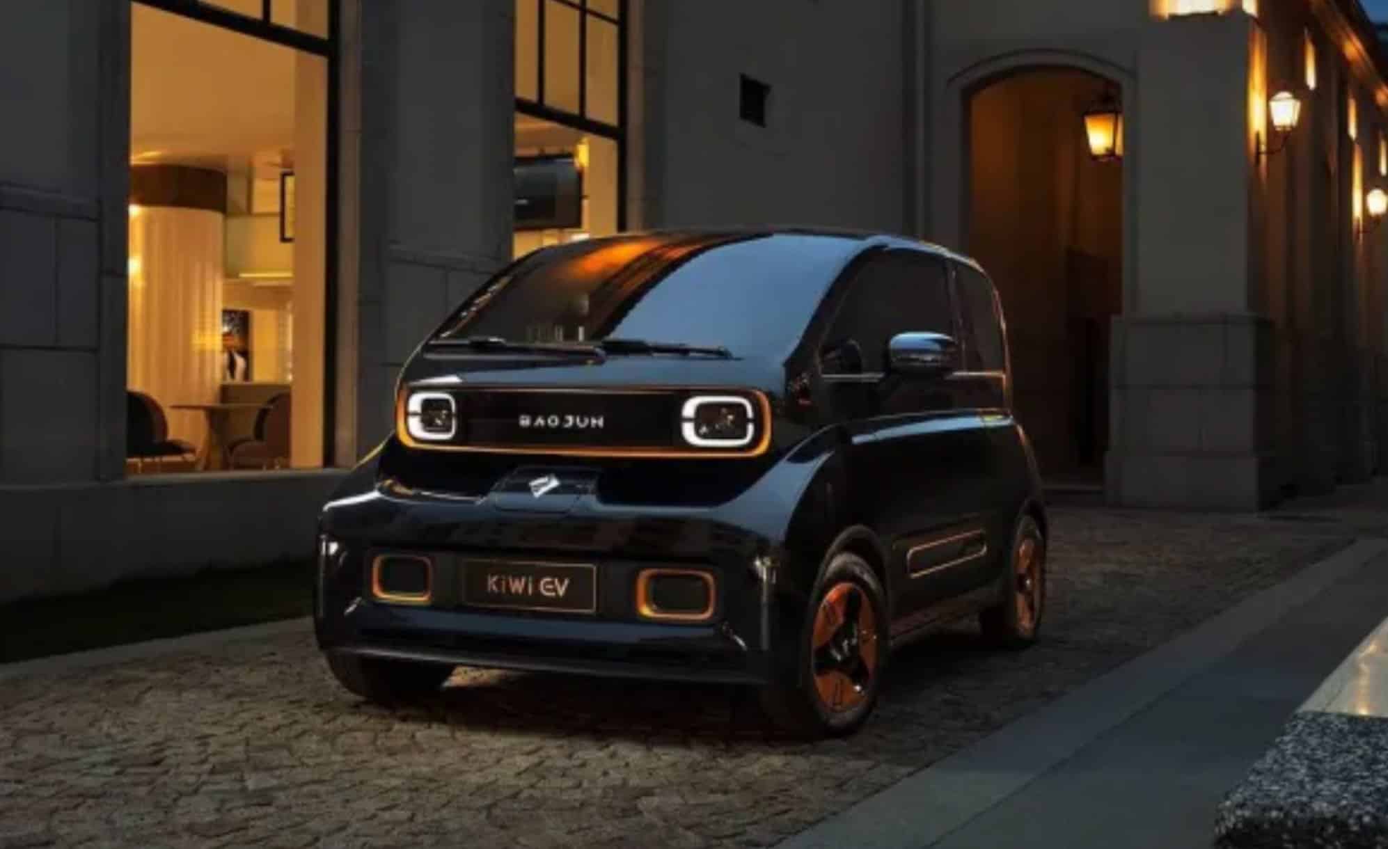 Black Baojun KiWi electric city car parked outside a lit building at night.