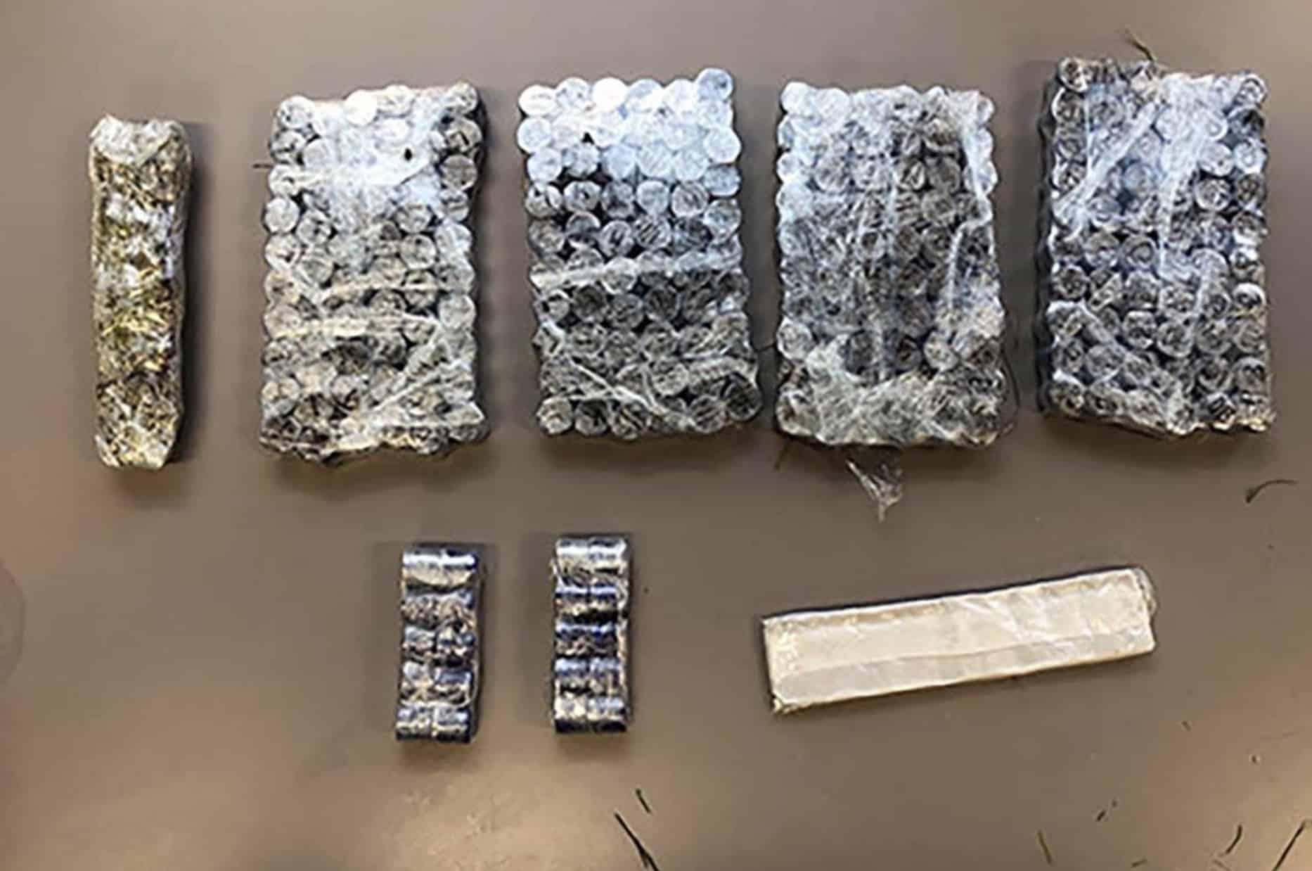 Plastic-wrapped drug bundles and two smaller packages arranged on a table as evidence.
