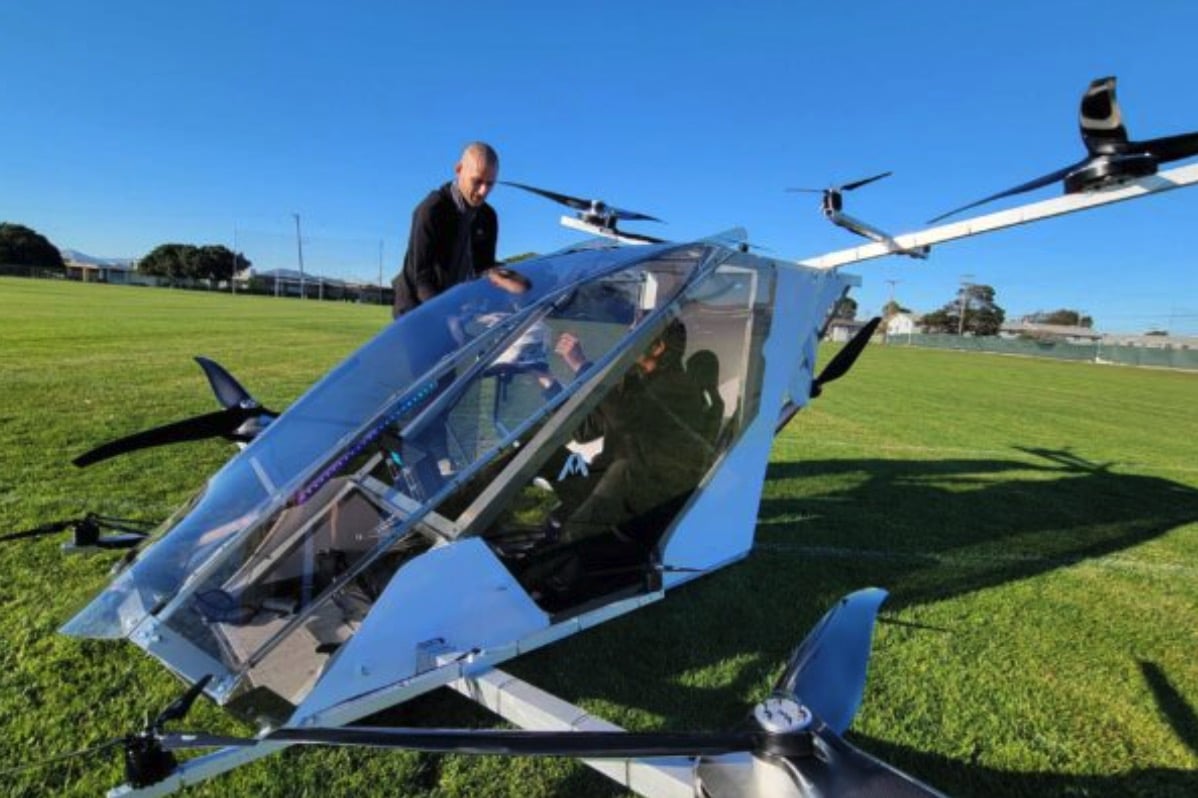 Experimental passenger eVTOL with mirrored canopy parked on a grass field.