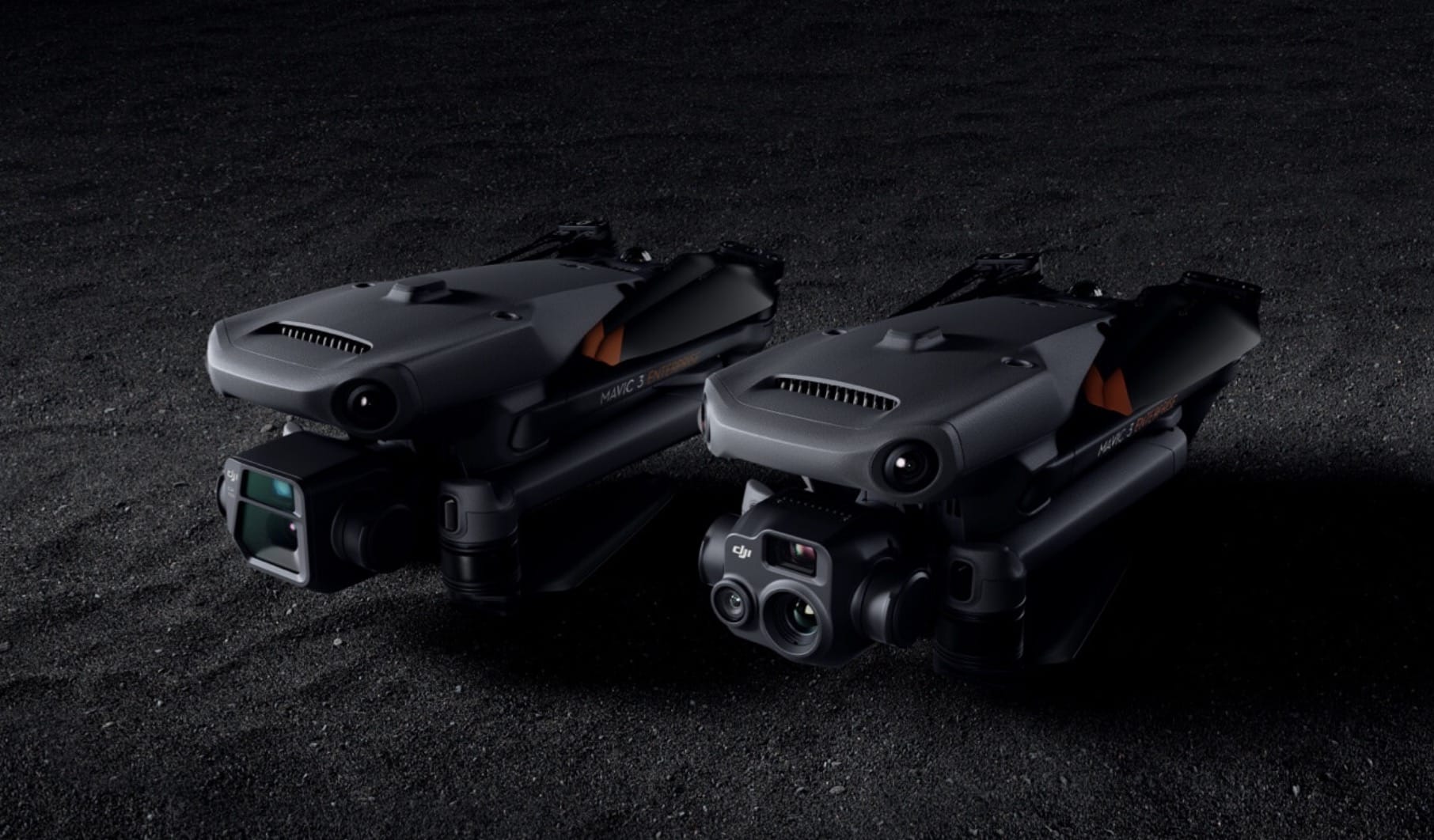 Two folded DJI Mavic 3 Enterprise drones on a dark textured surface.