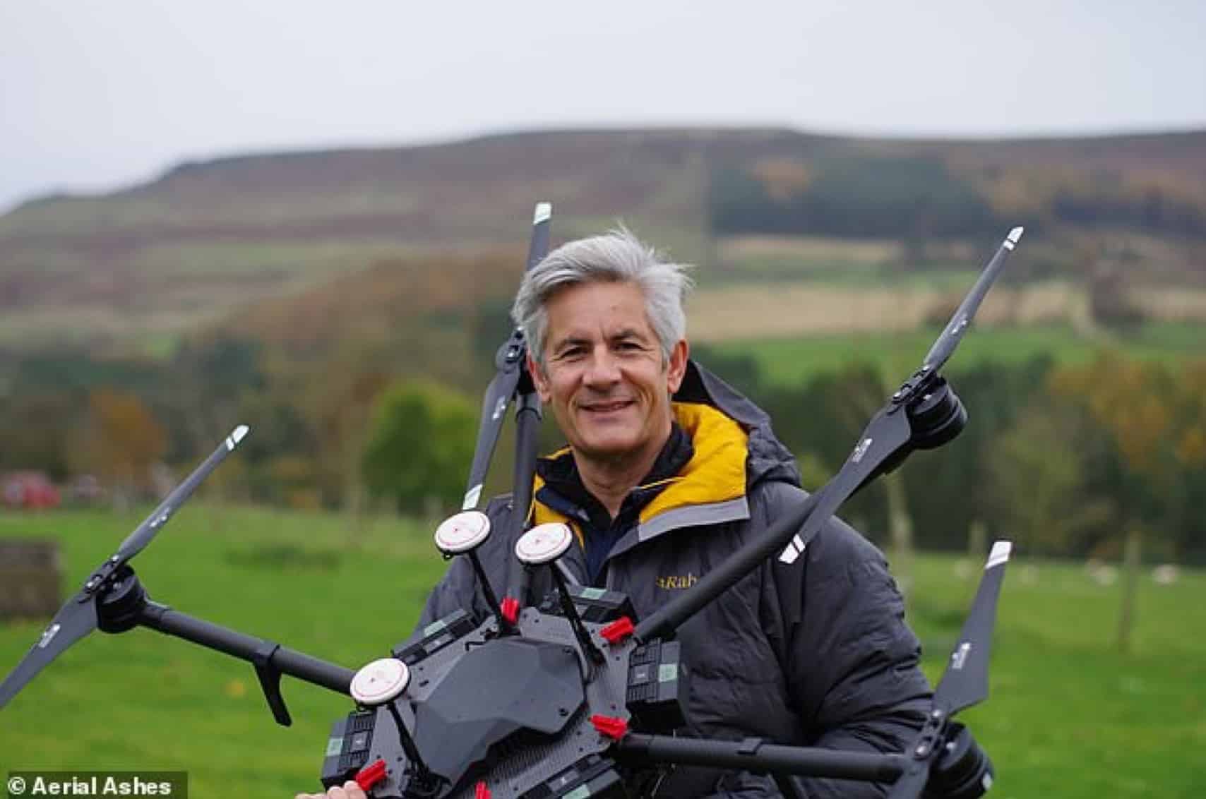 Aerial Ashes founder Christopher Mace carries his heavy-lift multirotor across a field.
