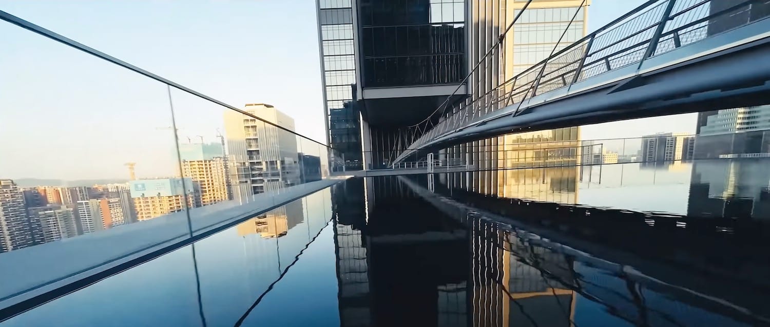 FPV frame of the DJI Sky City towers mirrored in a reflecting pool.