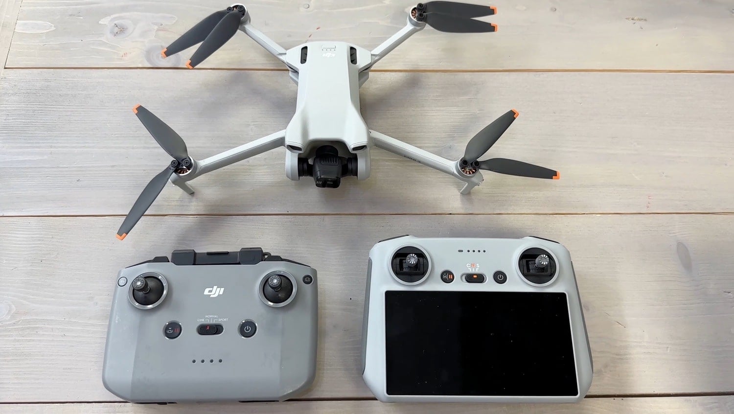 DJI Mini 3 laid out on wood beside the RC-N1 and DJI RC controllers.