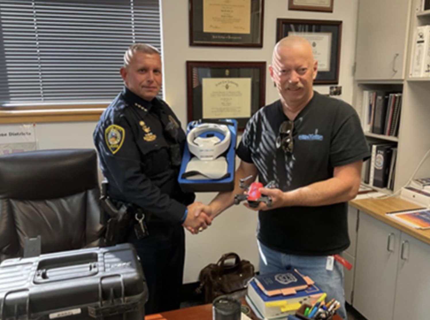Canon City police chief shaking hands with an Airborne Works representative over a drone case.