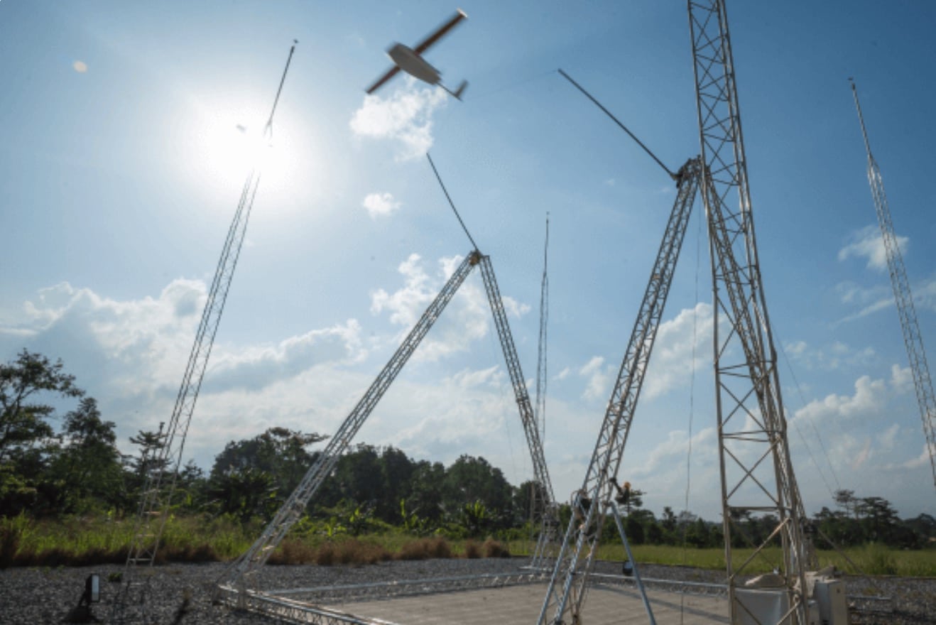Zipline launch and recovery towers at a Rwandan distribution center under blue sky.