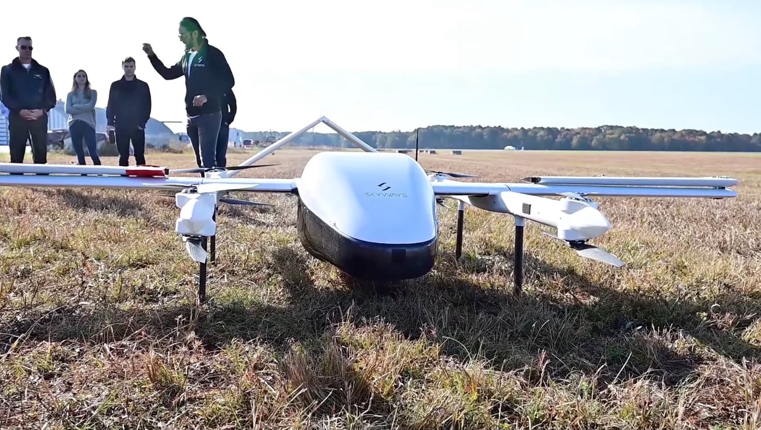 An unmanned cargo aircraft delivers supplies to a Navy ship underway at sea.