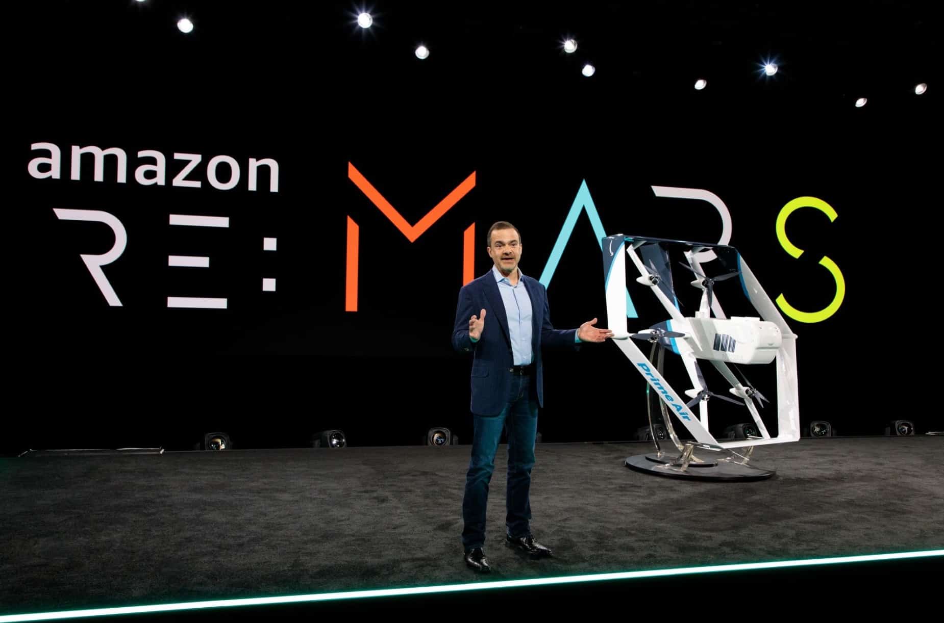 A presenter unveils an Amazon Prime Air delivery drone on the re:MARS stage.