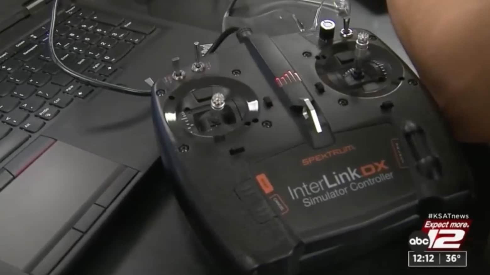 A Spektrum InterLink DX simulator controller resting on a laptop keyboard.