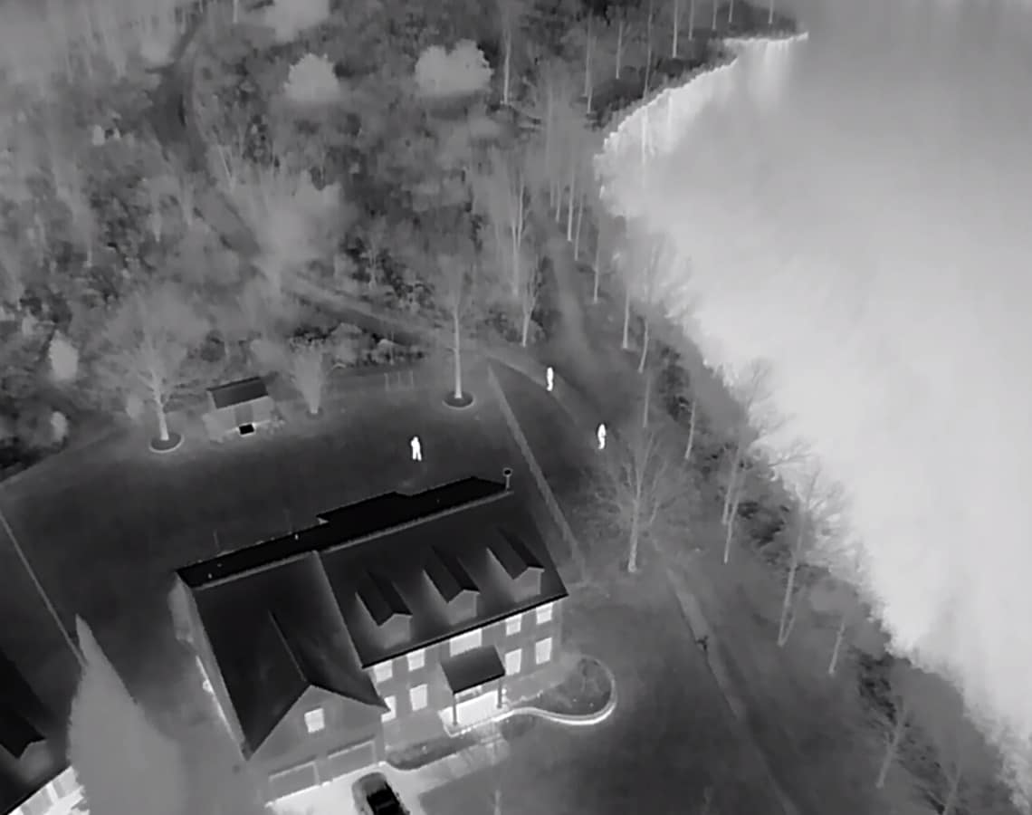 Three ground searchers showing clearly in thermal at the edge of the woods.