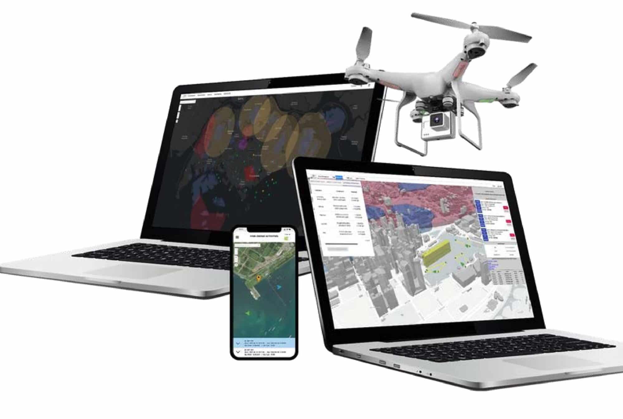 Laptops and a phone display airspace mapping software beside a white Phantom drone.