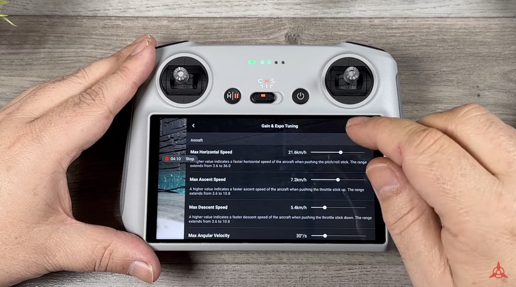Hands holding a DJI RC displaying the gain and expo tuning menu.