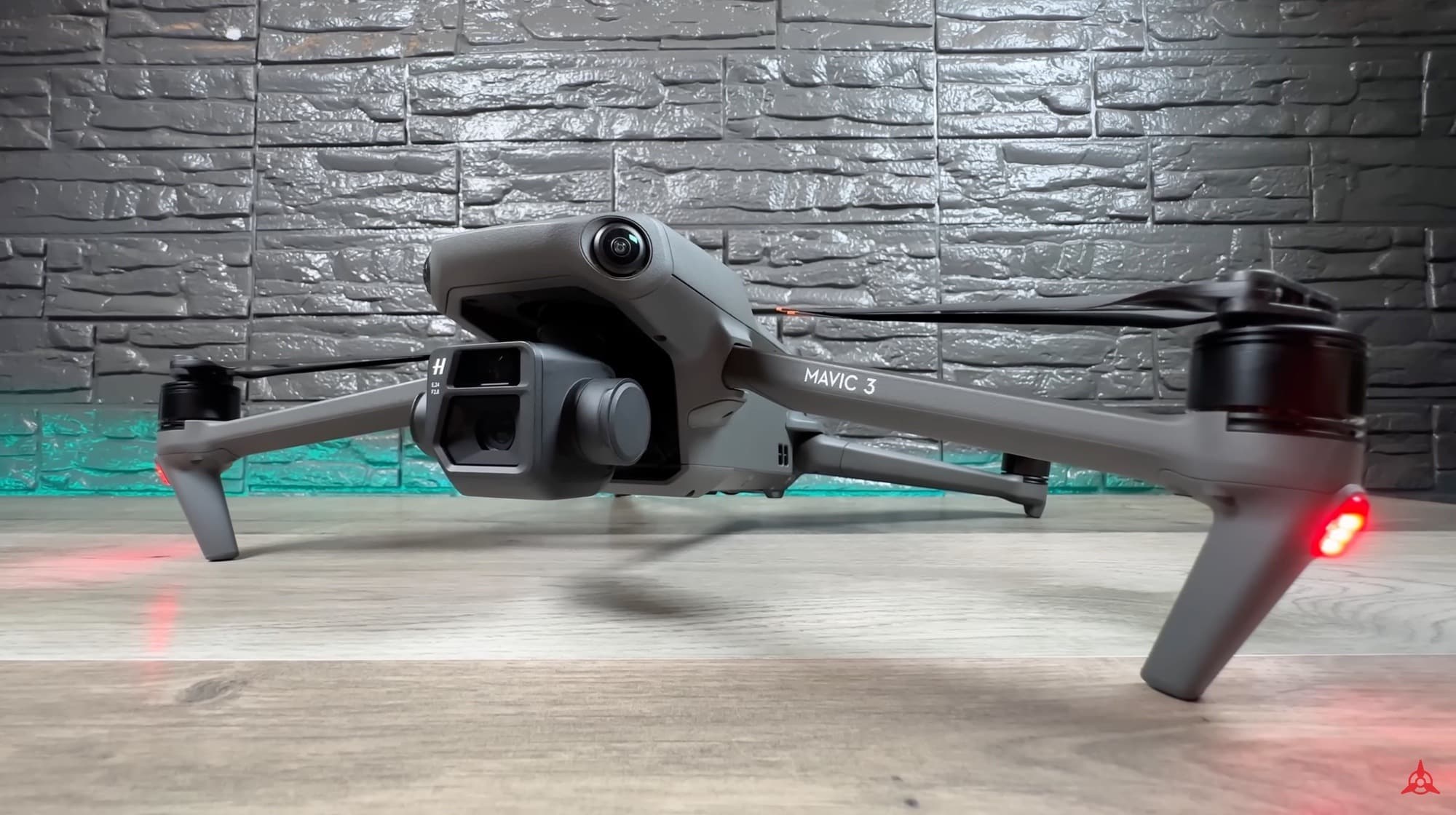 DJI Mavic 3 lifting off from a wooden floor in front of a stone wall.