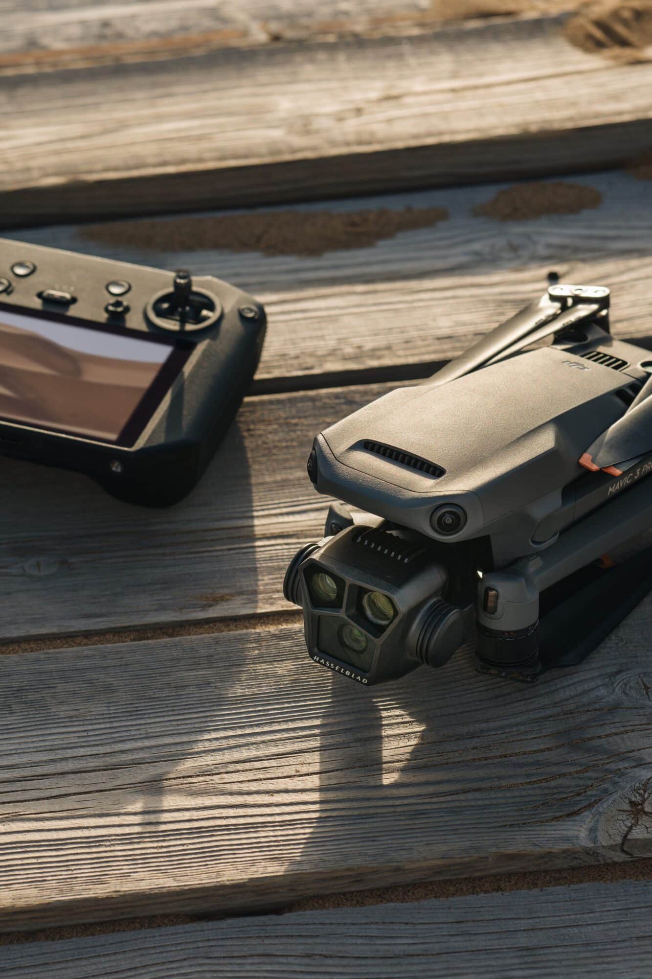 DJI Mavic 3 Pro folded beside its RC Pro controller on weathered decking.