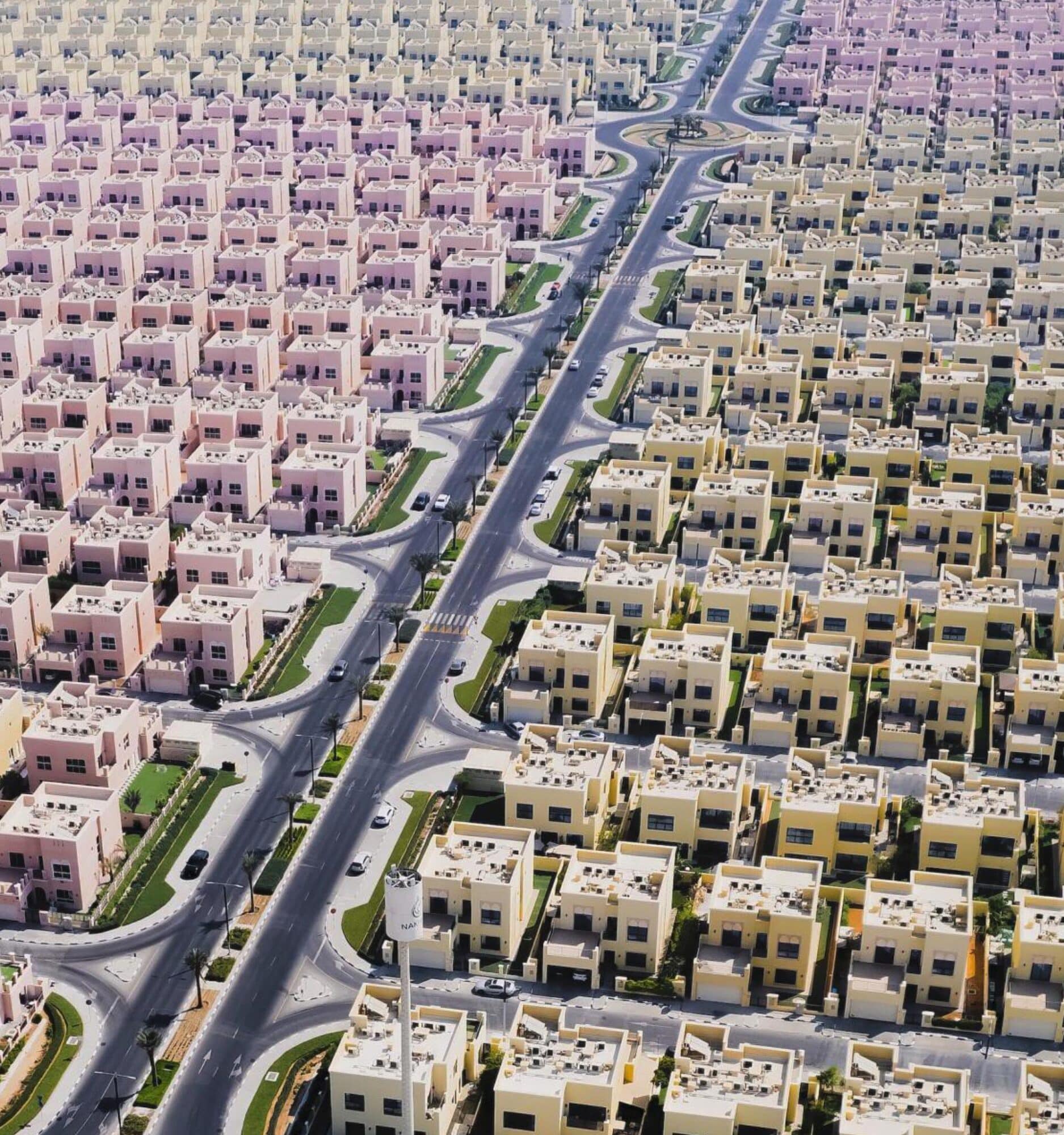 Suburban Dystopia by Florian Kriechbaumer. Situated on the fringes of Dubai in the United Arab Emirates, a specially constructed residential community showcases homes of a uniform design. These residences are distinguished by their dual-color scheme and are systematically laid out along a grid-like street network.