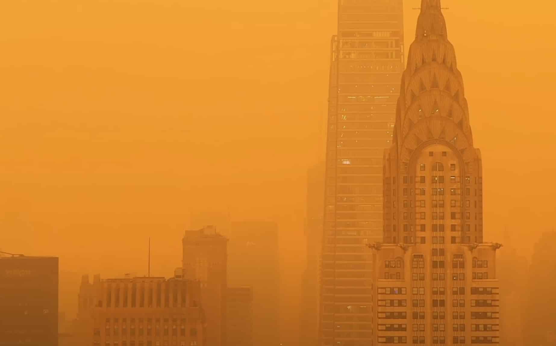 Chrysler Building barely visible through thick orange wildfire haze over Manhattan.