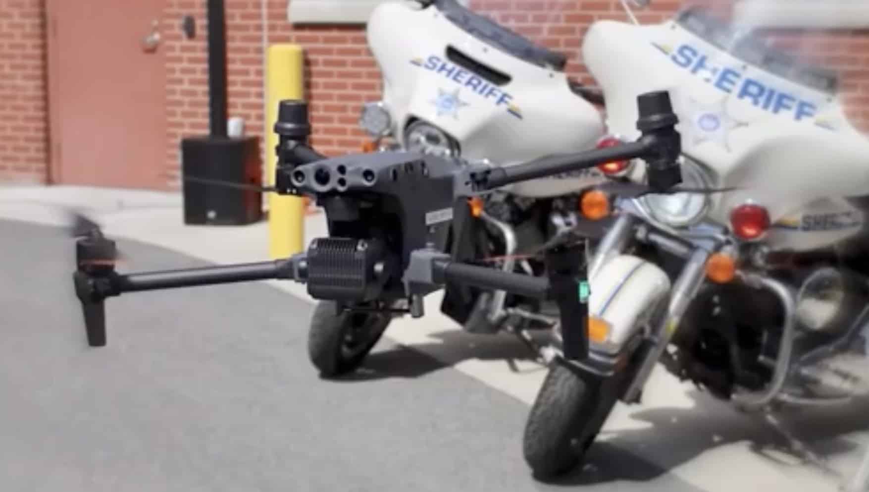 Sheriff drone parked on pavement in front of two police motorcycles.