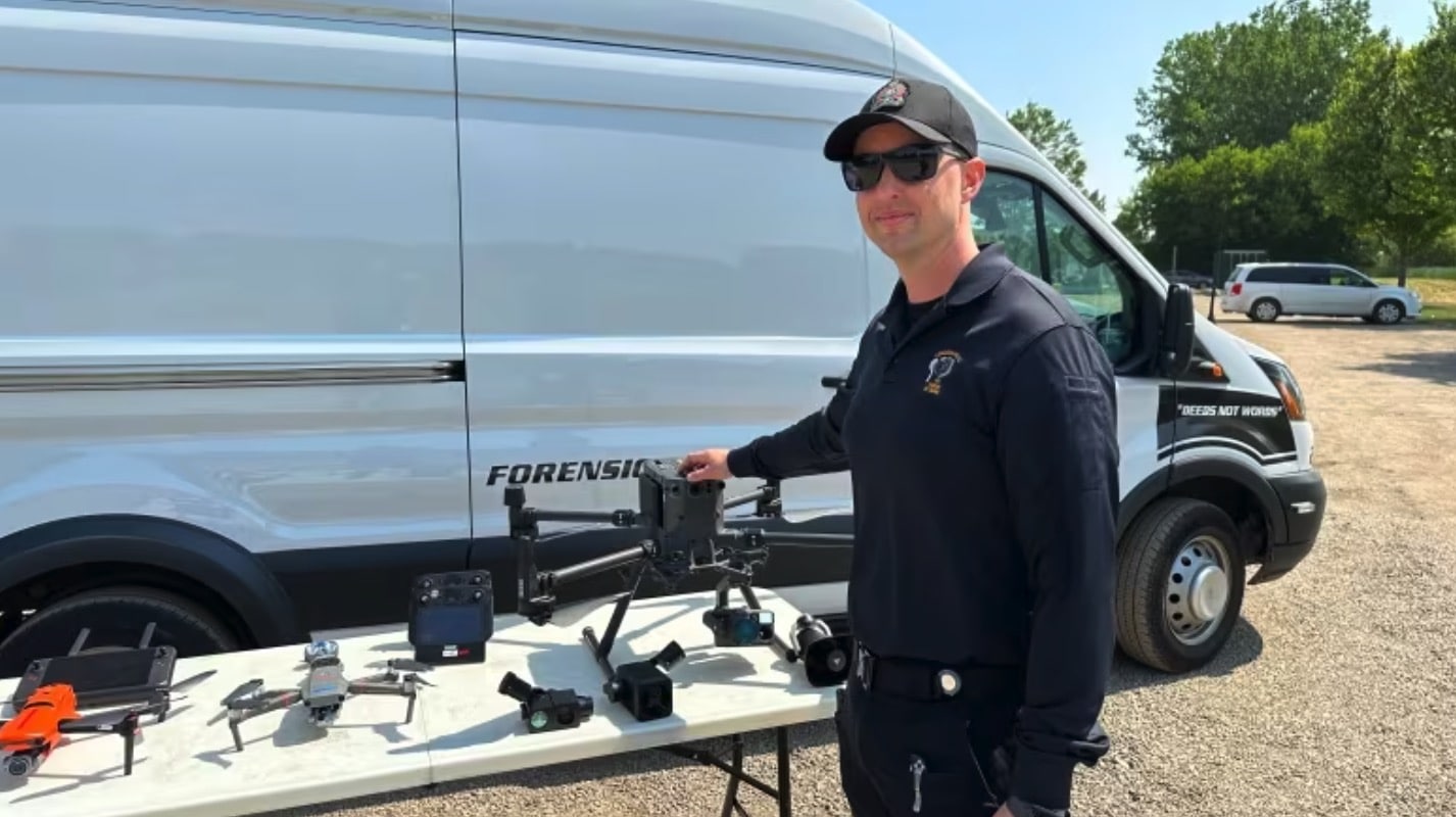 Officer beside a forensics van with police drones laid out on a table.