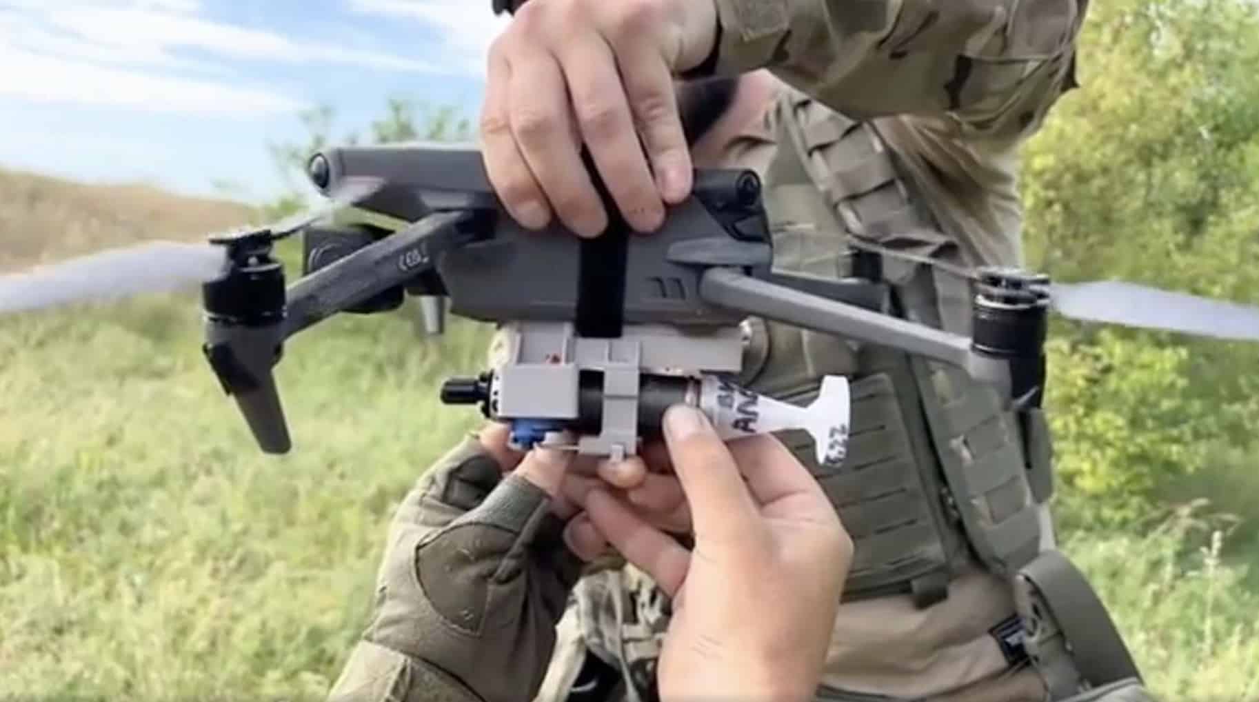 Hands fit a custom payload release beneath a DJI Mavic 3 in the field.
