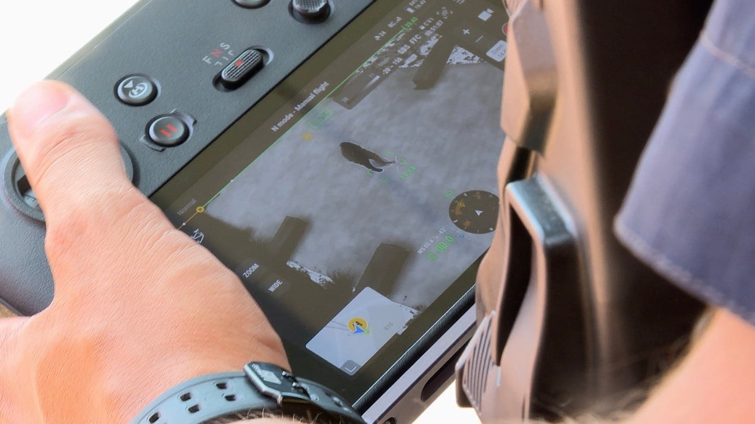 Close-up of a thumb on a drone controller screen showing the flight map.