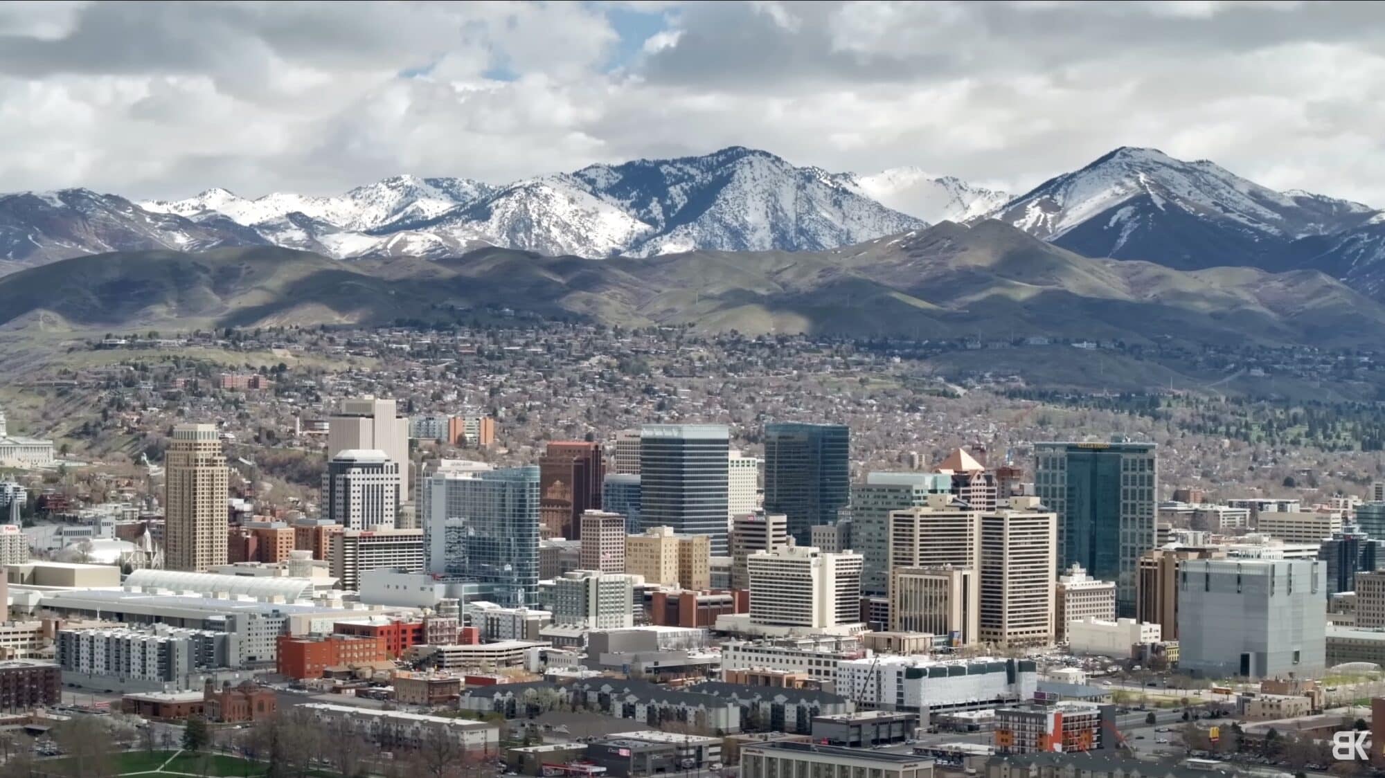 The same skyline at 70mm, compression pulling the mountains close behind the buildings.