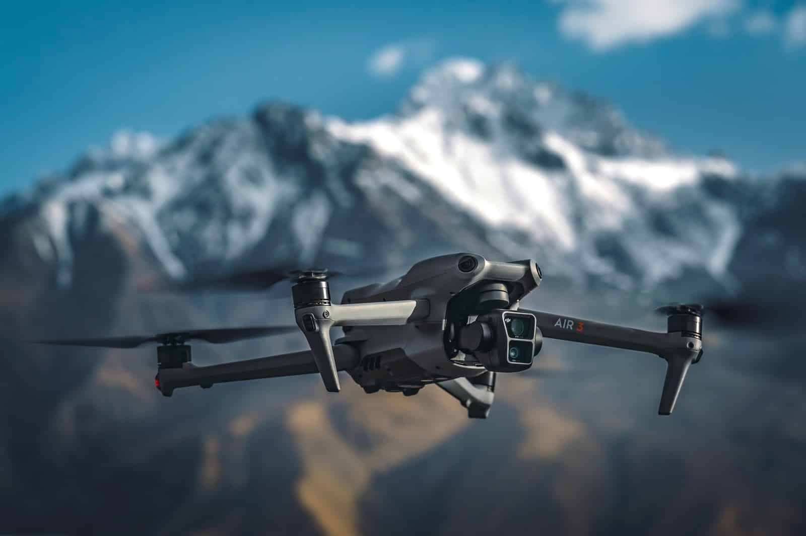 DJI Air 3 flying with snow-capped mountains behind it.