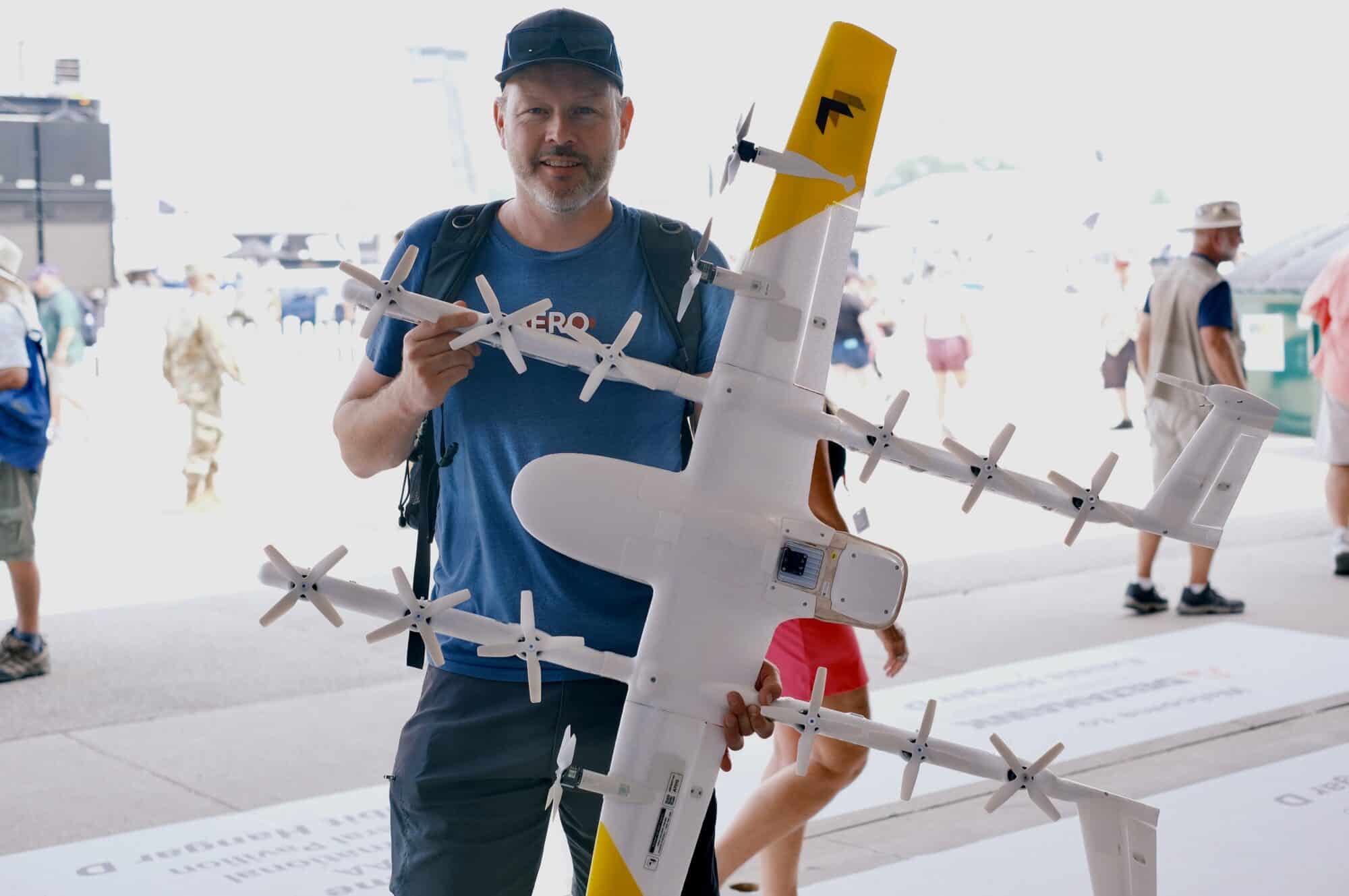 Haye Kesteloo, Founder and Senior Editor of DroneXL holding the Wing Delivery Drone at Oshkosh 2023. Wing and Apian Soar to Healthcare Heights! Medical Deliveries in Europe: Wing and Apian Soar to Healthcare Heights!