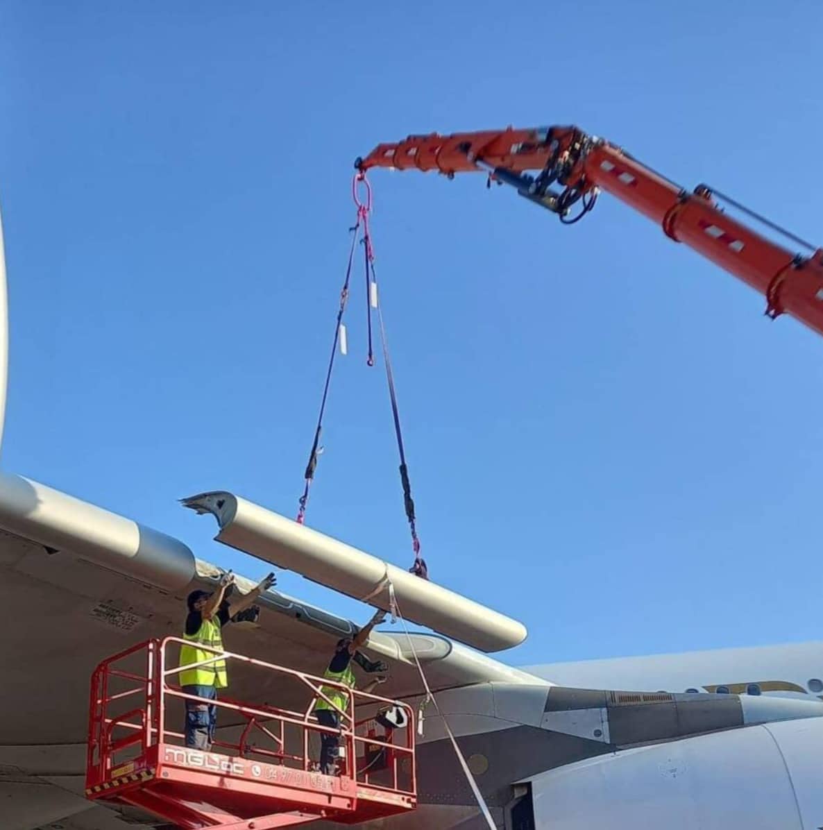 Crane lifting a radome away from an Airbus A380 nose as technicians watch.