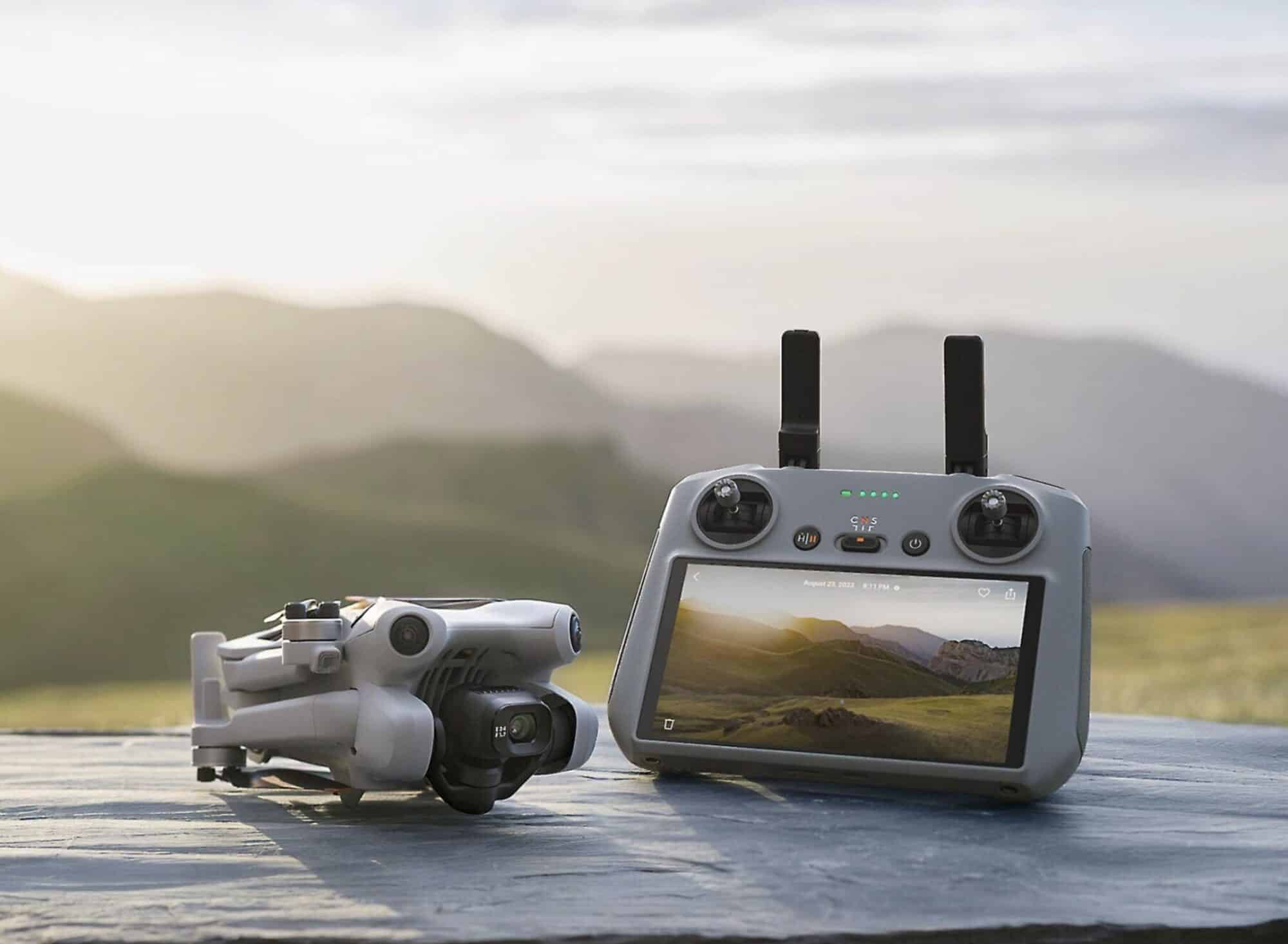 DJI Mini 4 Pro resting beside the RC 2 controller with mountains behind.