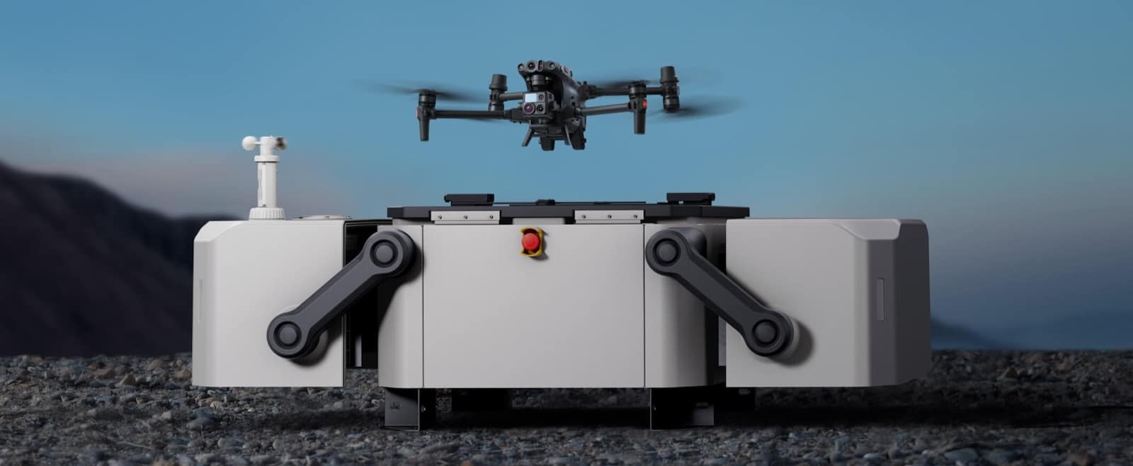 DJI Dock open with an enterprise drone on its pad below mountains.