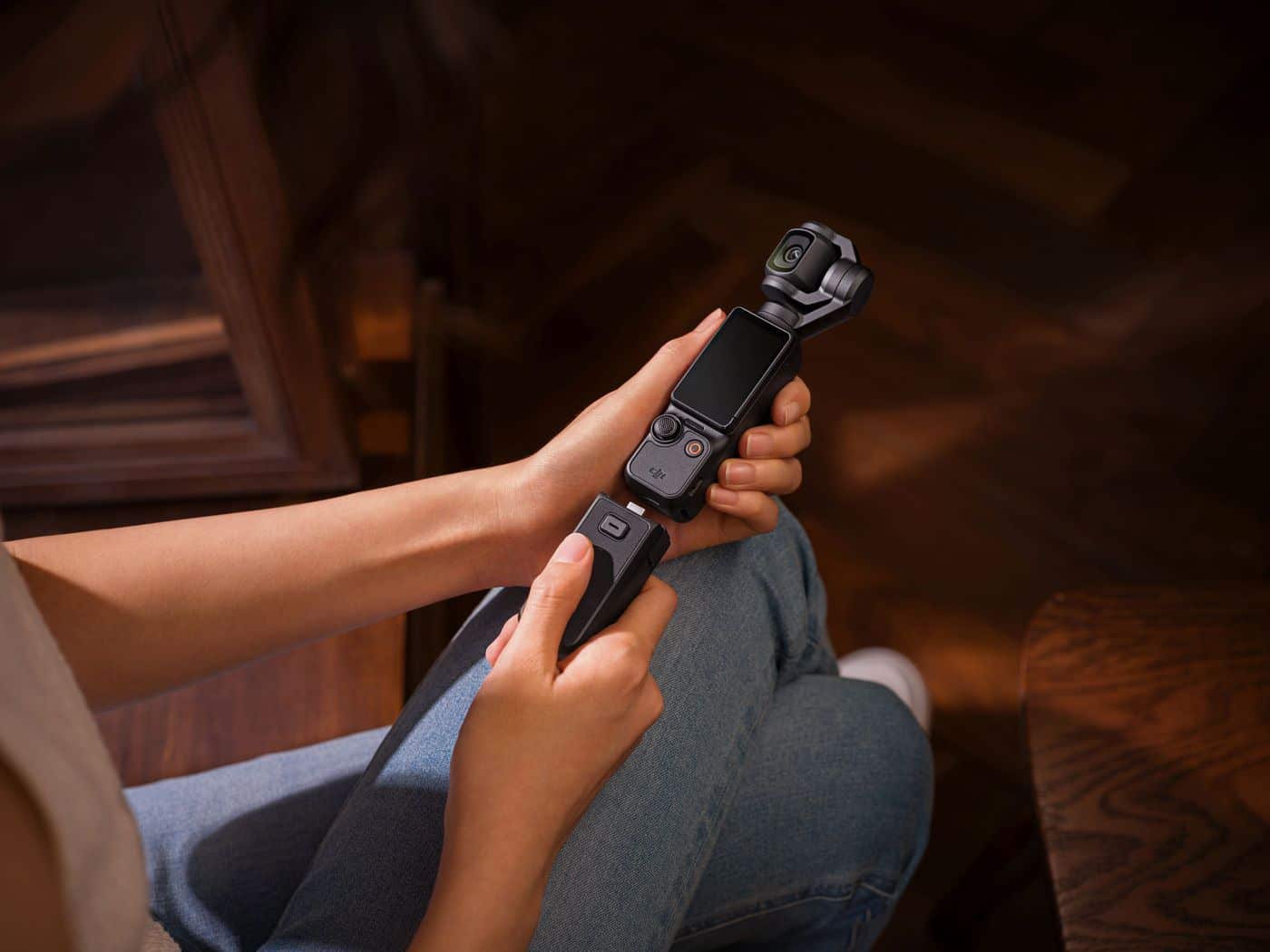 Person seated indoors holding a DJI Pocket 3 with its screen rotated.