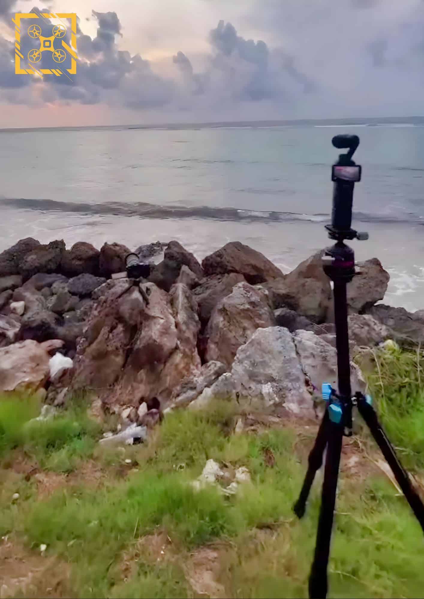 Leaked photo of a DJI Osmo Pocket 3 on a tripod beside a rocky shore.