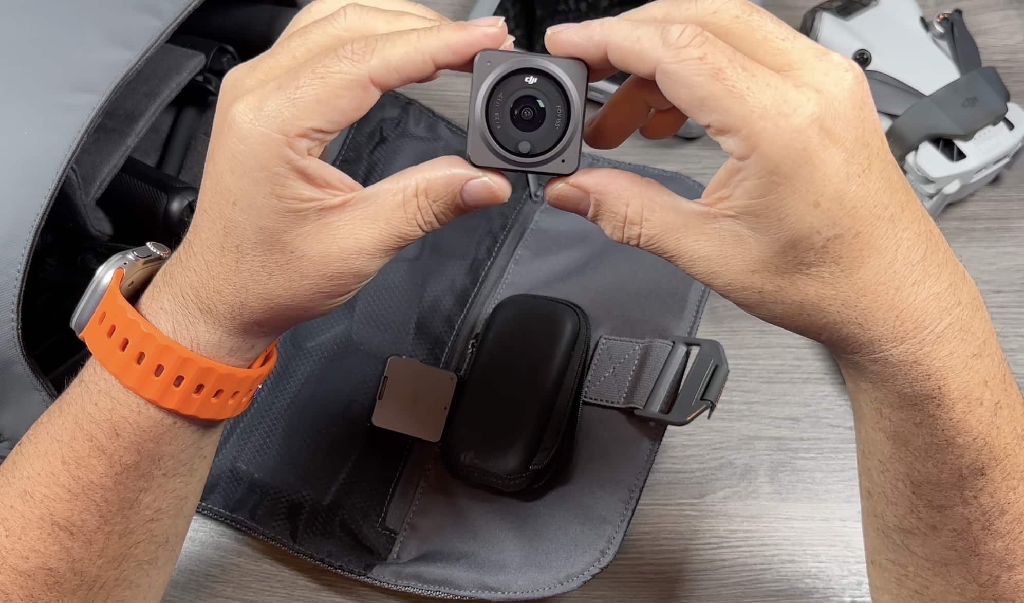 Hands clip a DJI Osmo Action camera onto a chest mount strap.