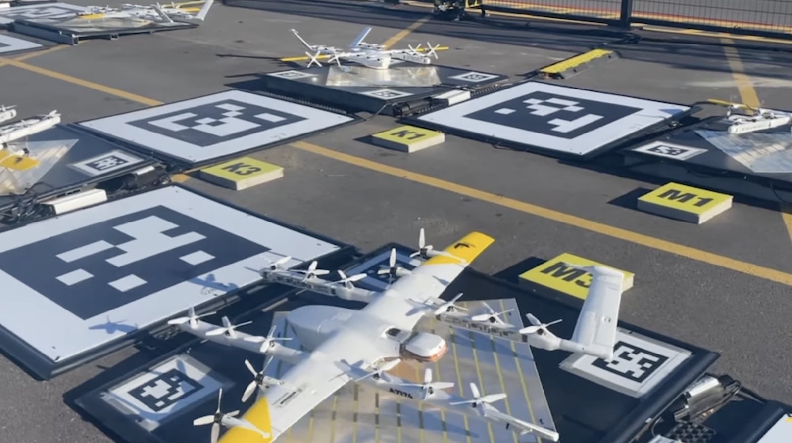 Wing delivery aircraft parked on marked pads at a loading site.
