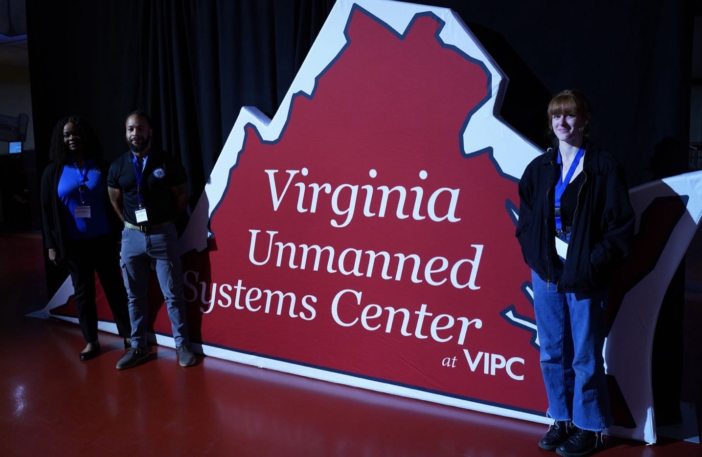 Attendees pose beside a Virginia Unmanned Systems Center sign at the conference.