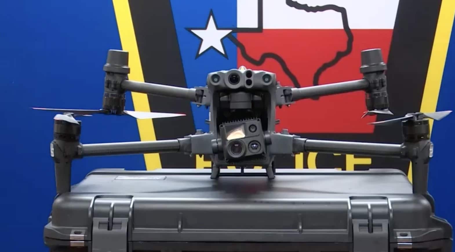 Police drone perched on a hard case in front of a Texas flag backdrop.