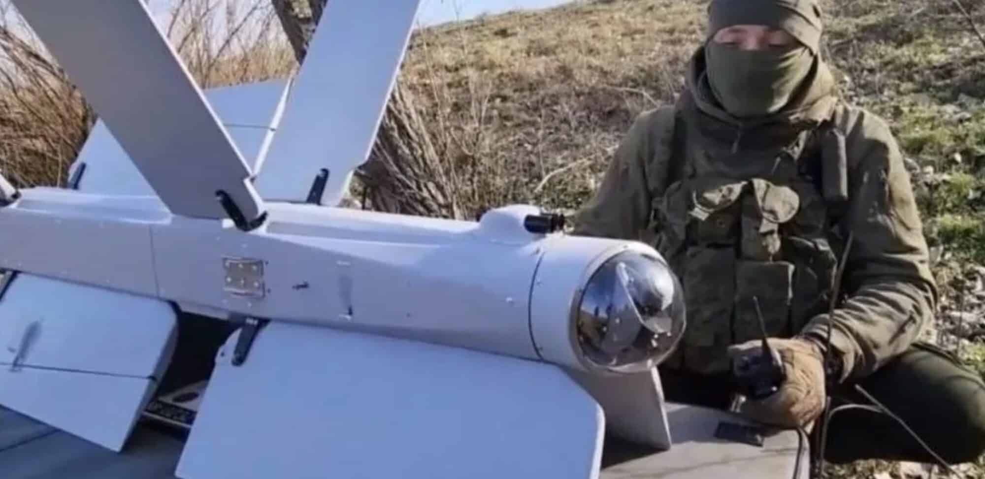Masked soldier crouched beside a Lancet loitering munition on its rail.