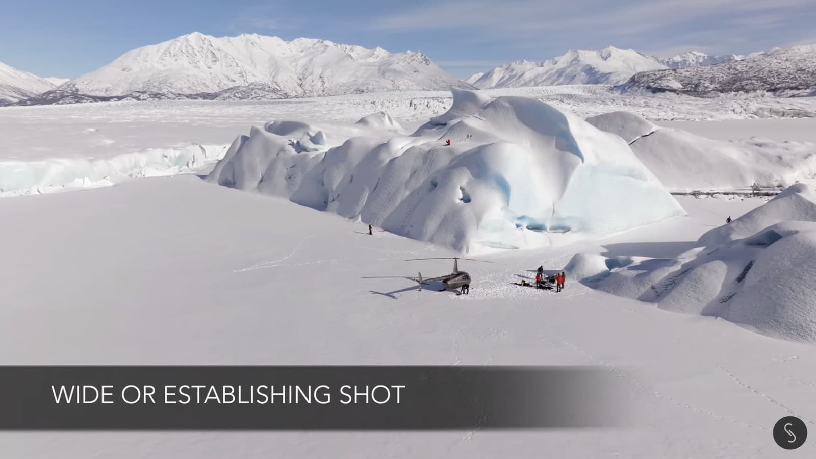 Wide drone frame establishing the frozen Alaska lake around the ice climbers.